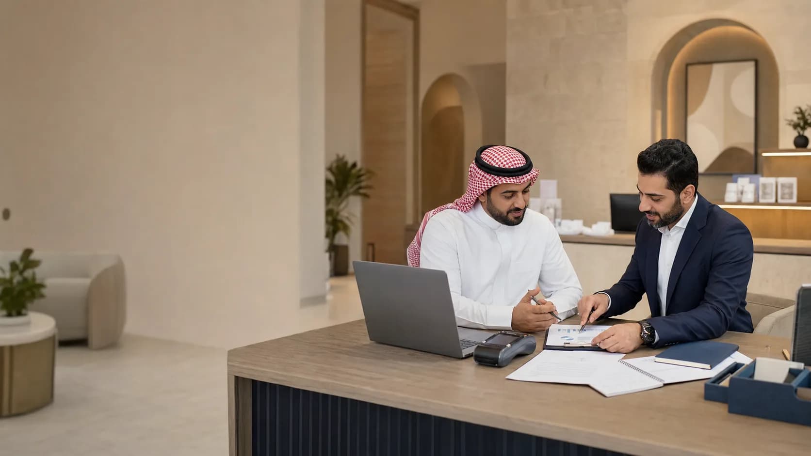 A Madinah business owner reviewing organised financial reports with a finance professional